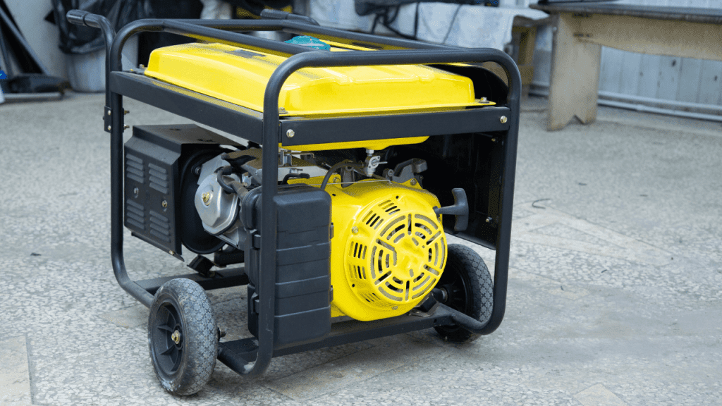 A portable generator resting on a flat concrete surface, its metal frame and two wheels on either end keeping it stable while it runs to provide backup power during an outage.