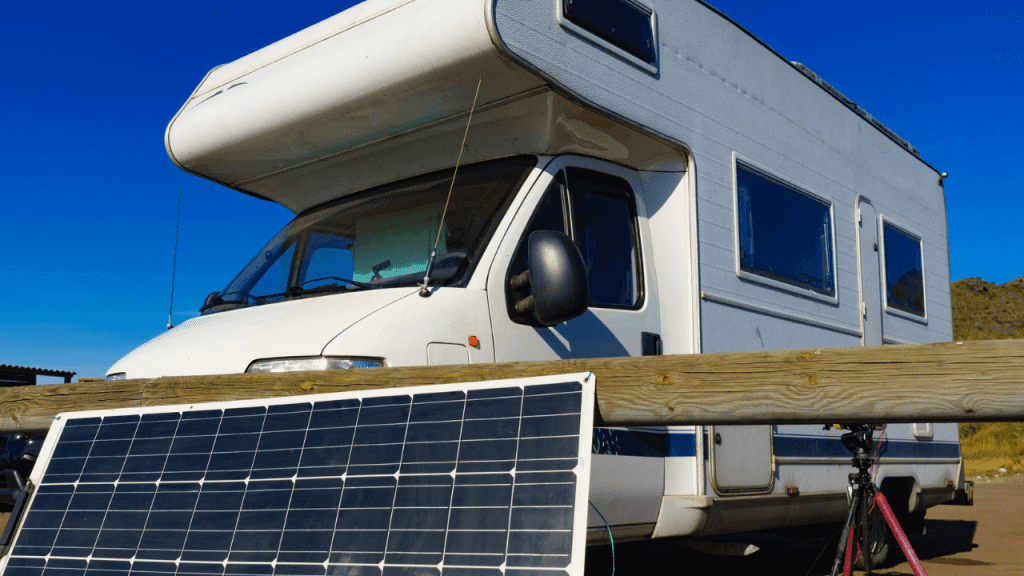 Foldable solar panels placed on a stand beside a parked caravan, angled toward the sun to efficiently generate electricity for charging batteries and running appliances during camping.