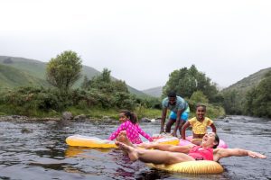 People enjoying recreational water activities using inflatable floats in a natural outdoor setting, highlighting fun water toys for a camping trip.