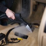 Handheld vacuum being used to deep clean red dust and sand from a caravan floor.