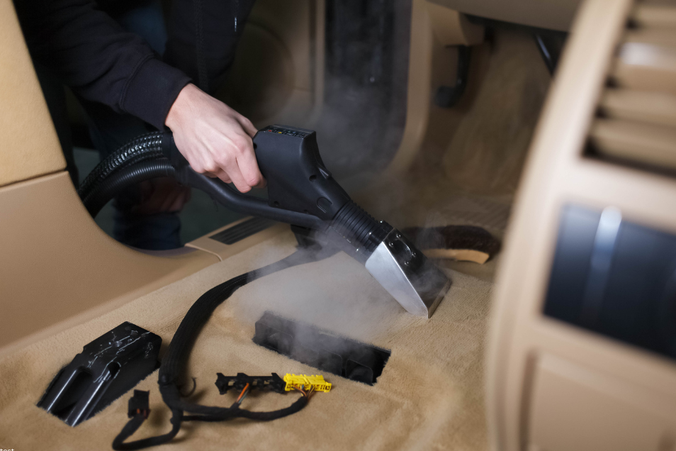 Handheld vacuum being used to deep clean red dust and sand from a caravan floor.